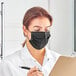 A woman wearing a Lavex black protective face mask and holding a pen and clipboard.