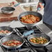 A man cooking food in a Vigor aluminum fry pan.