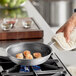 A Vigor A3000 series aluminum fry pan with scallops cooking on a stove.