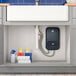 A white rectangular GE tankless electric water heater with a blue button above a kitchen sink.