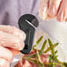 A gloved hand using a Tangibles black plastic magnetic bag opener to snip a bag