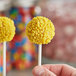 A close up of a hand holding yellow Yum Crumbs Lemon Pound Cake pops.