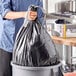 A woman holding a black Glad drawstring trash bag.