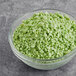 A bowl of green Yum Crumbs pistachio crumb topping.