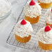 Cupcakes with Coral Bay sweetened coconut frosting and raspberries on a cooling rack.