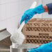 A person in blue gloves using a white O-Cedar utility brush to clean a silver pot.