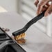 A person cleaning a metal surface with an O-Cedar brass detail brush.