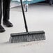 A person using an O-Cedar commercial broom to sweep the floor.