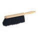 An O-Cedar black Tampico counter duster with a wooden handle.