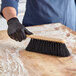 A person using an O-Cedar counter duster brush to clean a table