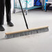 A person sweeping the floor with an O-Cedar commercial broom.