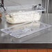 A clear plastic Vollrath Super Pan slotted cover on a container of cottage cheese on a counter.