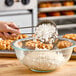 A person pouring Belgian Pearl Sugar into a bowl of waffle dough.