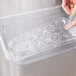 A person's hand holding a Vollrath clear plastic drain tray over a counter.