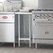 A Regency galvanized steel undershelf under a stainless steel work table.