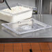 A Vollrath clear plastic slotted lid on a food container on a counter.