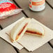 A Smucker's Uncrustables sandwich with peanut butter and jelly on a napkin.