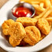 A plate of unMEAT Vegan Chick'n Nuggets and french fries with a bowl of ketchup.