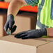 A person wearing Ansell HyFlex gloves with black palm coating working on a box.