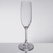 A clear plastic Carlisle champagne flute with a stem on a table.