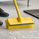 A white pole with a black stripe and a yellow Lavex brush head on the floor being used for cleaning.