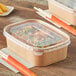 A rectangular Kraft paper take-out container with food inside on a table.