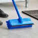 A blue Lavex brush head with a squeegee on the floor.