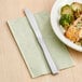 A Choice medium weight stainless steel dinner knife on a plate of food on a table.