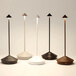 A group of Zafferano America Pina Pro table lamps in different colors on black poles.