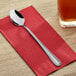 A Choice Milton stainless steel iced tea spoon on a red napkin.