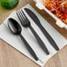 A black plastic fork and knife on a white napkin.