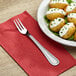 A plate of baked potatoes with white sauce and green onions with a Choice Milton stainless steel oyster fork on the side.