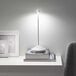 A Zafferano America Pina white cordless table lamp on a stack of books.