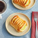 A plate with a Bridor lemon danish pastry on it next to a cup of coffee.