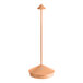 A Zafferano America Pina table lamp with a copper base and orange shade.