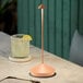 A Zafferano America Pina copper table lamp on a marble table near a drink with a lemon slice.