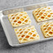 A gray tray of four square Bridor mango pastries.