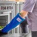 A person wearing a blue Tucker Safety Products oven mitt taking food out of the oven.