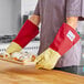 A man holding a tray of pastries wearing Tucker Safety Products oven gloves.