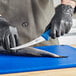 A person in black gloves using a Victorinox curved boning knife to cut a fish.