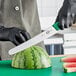 A person wearing a black glove uses a Victorinox curved serrated bread knife to cut a watermelon.