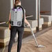 A woman vacuuming a wood floor with a ProTeam backpack vacuum.