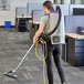 A woman using a ProTeam GoFit 10 backpack vacuum with a black hose to vacuum the floor.