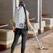 A woman using a ProTeam backpack vacuum to clean a room in a corporate office.