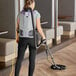 A woman wearing a ProTeam GoFit backpack vacuum cleaning a wood floor.