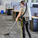 A woman using a ProTeam GoFit backpack vacuum to clean a carpet in a corporate office.