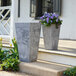 Two Novelty Manufacturing Co. Ella square gray planters with purple flowers on an outdoor patio table.