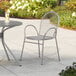 A Lancaster Table & Seating Harbor Gray Steel Mesh Outdoor Arm Chair on a patio.