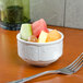 A bowl of fruit in a Tuxton Chicago bright white bowl on a table.