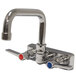 A chrome Advance Tabco wall mount faucet with lever handles.